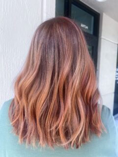 Shoulder-length copper waves with darker roots.