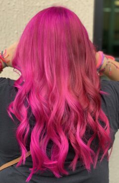 Long vivid pink hair with curled ends.
