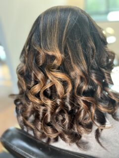 Dark brown curls with caramel highlights.