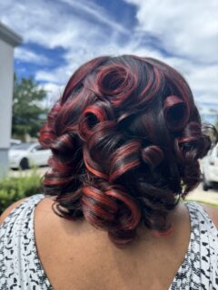 Dark hair with vivid red highlights styled in large curls.