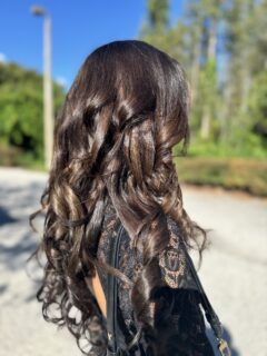 Long dark brown hair styled in glossy spiral curls.